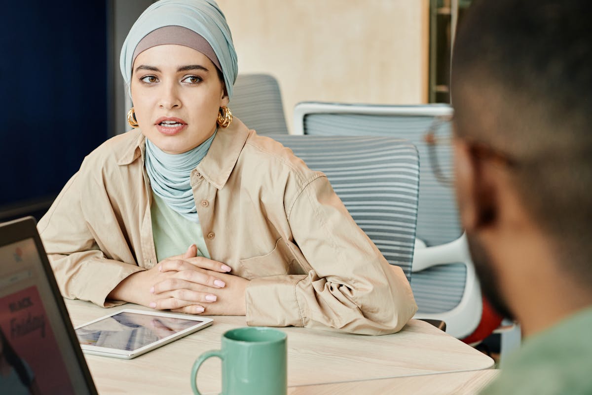 Woman Wearing Headscarf Sitting on Table with Tablet