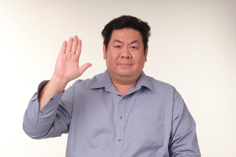 Man Raising Hand in a Neutral Indoor Setting