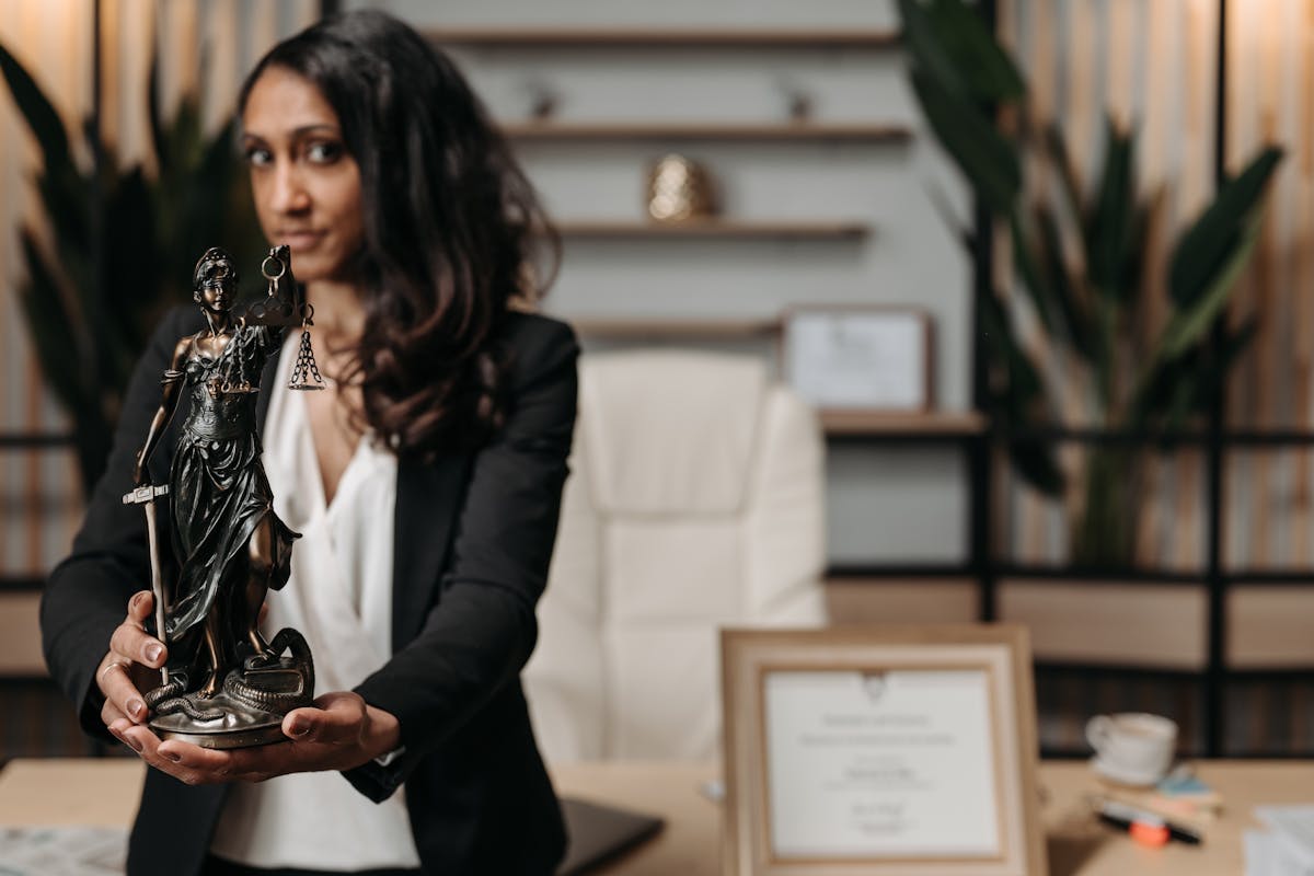 Woman in Black Blazer Holding Lady Justice Statue