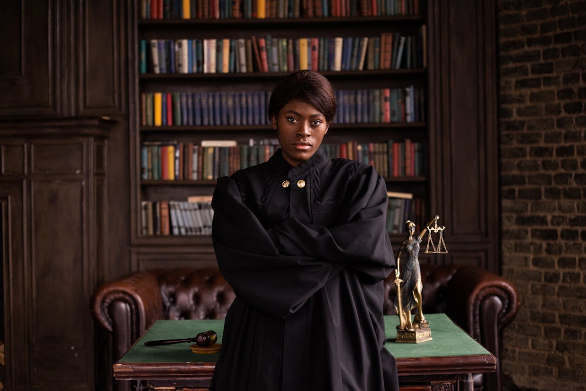 Woman in Black Robe Standing Beside Wooden Table