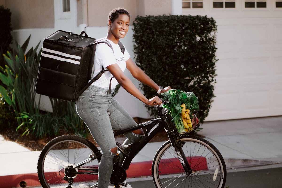 Woman in White Shirt and Denim Jeans Riding on Black Bicycle