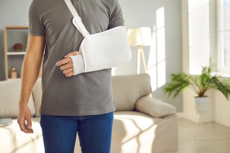 Crop close up of injured man with bandage on broken arm. Pain in hand. Unhealthy guy wear splint sling having elbow or wrist injury have rehabilitation process. Healthcare and rehab concept.
